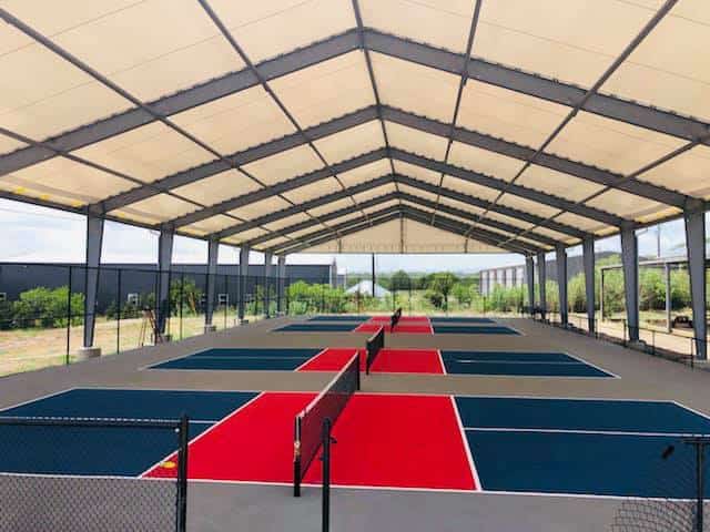 Covered pickleball courts illuminated by bright LED lights for all-weather play.