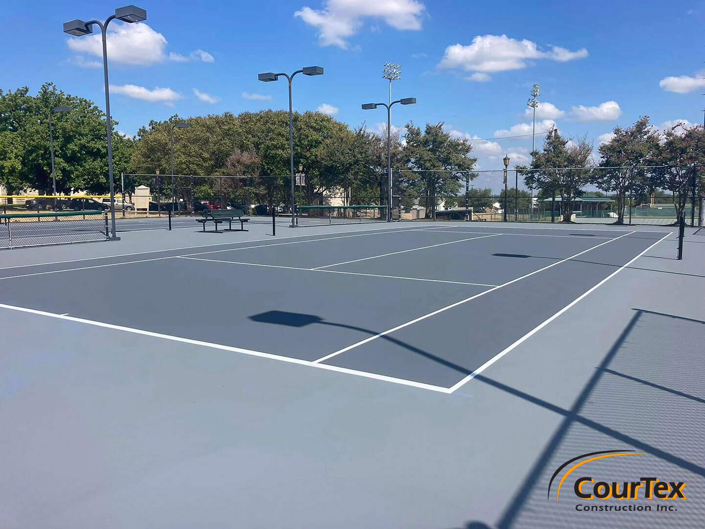 Newly built outdoor tennis courts with smooth surfaces, crisp lines, and bright LED lighting for nighttime play.